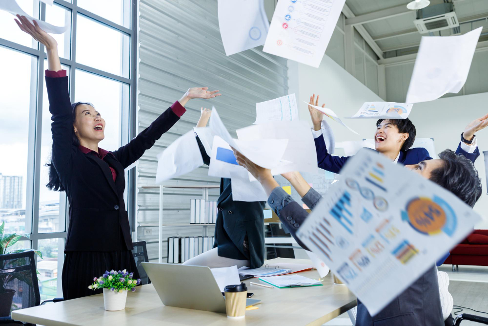 successful-happy-workers-group-asian-business-people-with-diverse-genders-lgbt-threw-up-business-plan-document-paper-into-air-meeting-room-officeemotionally-satisfied-with