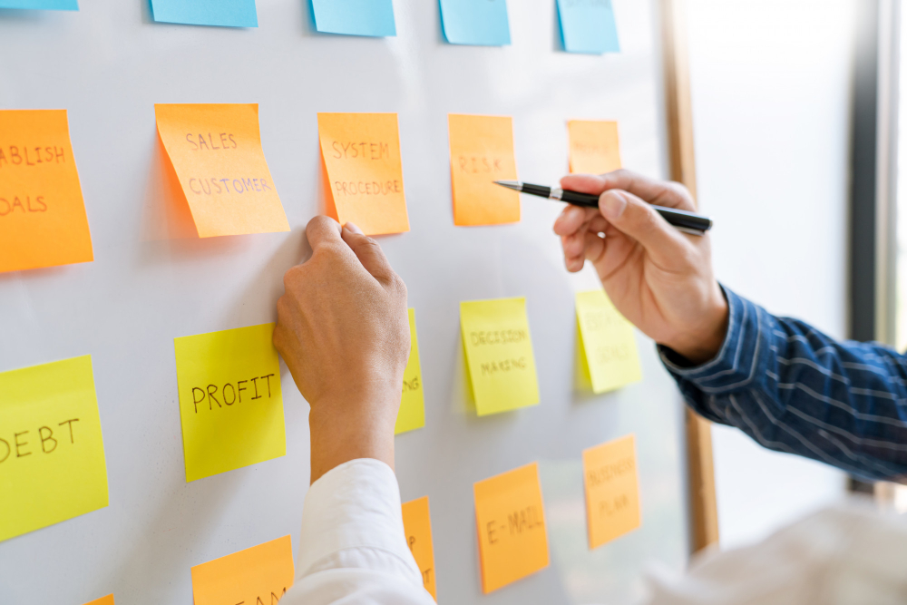 young-business-workers-posting-with-sticky-notes-stickers-reminders-creative-brainstorming-board-colleague-modern-co-working-space